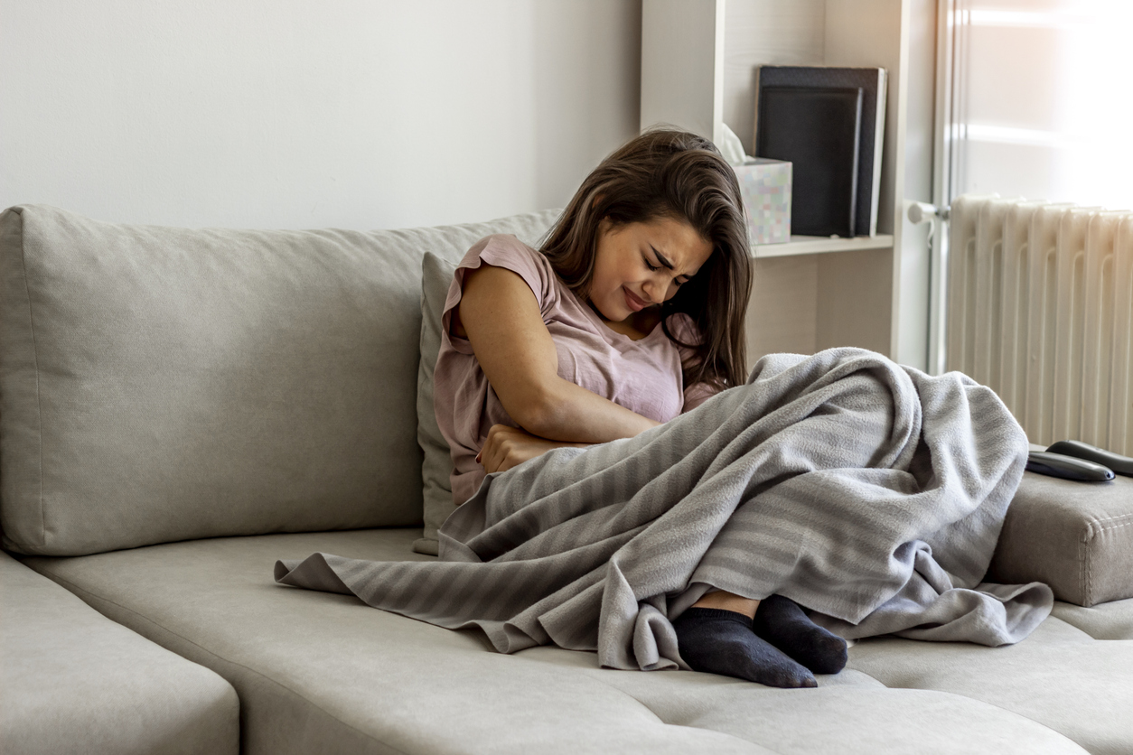 Unhappy woman holding hands on stomach suffering from abdominal pain.